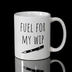 May include: White ceramic mug with the text "FUEL FOR MY WIP" in black, along with a black pen illustration. The mug has a curved handle and is set against a black background.