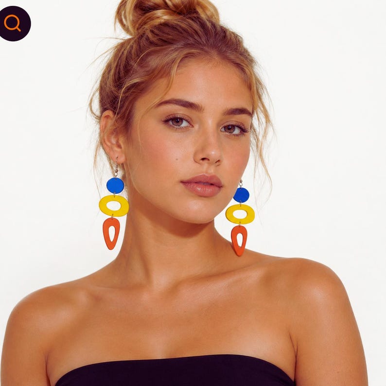 May include: Colorful abstract earrings with a blue circle, yellow oval, and orange teardrop shape. The earrings are suspended from silver hooks. The design is modern and geometric, with a bold color palette.
