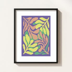 May include: Framed art print featuring a colorful abstract leaf design. The artwork showcases stylized leaves in shades of yellow, peach, and green against a purple background. The print is encased in a black frame.