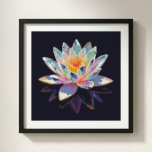 May include: A framed square wall art piece featuring a pixelated lotus flower illustration. The flower displays a vibrant palette of pastel pink, blue, yellow, and purple hues against a solid dark navy background, with a mirrored reflection below.