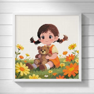 Könnte beinhalten: Ein Kreuzstichmuster mit einem jungen Kind mit braunen Zöpfen, das ein orangefarbenes Kleid trägt und in einem Feld aus gelben und orangefarbenen Blumen sitzt, während es einen braunen Teddybären hält. Das Bild ist in einem weißen quadratischen Rahmen.