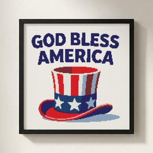 May include: Framed print with a patriotic theme. It shows a top hat in red, white, and blue, with white stars on the blue band. The words "GOD BLESS AMERICA" are printed above the hat in dark blue.