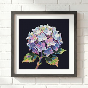 May include: A square framed wall art piece featuring a pixelated hydrangea flower illustration. The hydrangea displays shades of blue, purple, and pink petals against a solid dark navy background, with green and yellow variegated leaves on the stem.
