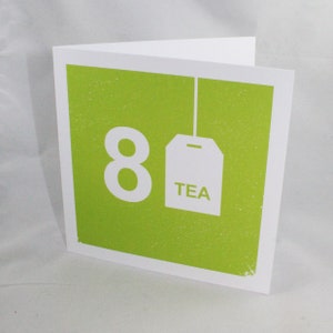 Könnte beinhalten: Eine grüne Karte mit einer weißen Zahl 8 und einem weißen Teebeutel mit dem Wort "TEA" darauf.