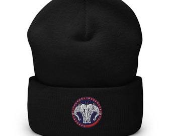 Puede incluir: Gorro negro con borde doblado. La parte delantera presenta un parche bordado circular con tres elefantes blancos, un borde rojo y azul y una franja roja en la parte inferior. El gorro está hecho de un material de punto suave.