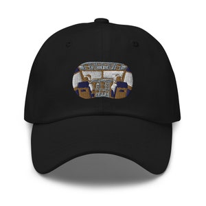 Puede incluir: Una gorra de béisbol negra con una imagen bordada de una cabina de avión. La cabina está detallada con costuras doradas y azules.