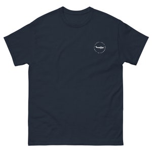 May include: A navy blue t-shirt with a white circle graphic featuring a small airplane and the text "A First Solo Flight in Command".