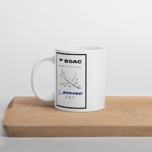 Può includere: Tazza in ceramica bianca con un'illustrazione in bianco e nero di un aereo Boeing 747. Il testo "BOAC Queen of the Skies" e "BOEING 747" è stampato sulla tazza.