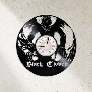 May include: Black vinyl record clock featuring a silhouette of a character from the anime Black Clover. The clock face has Roman numerals and a pink background.