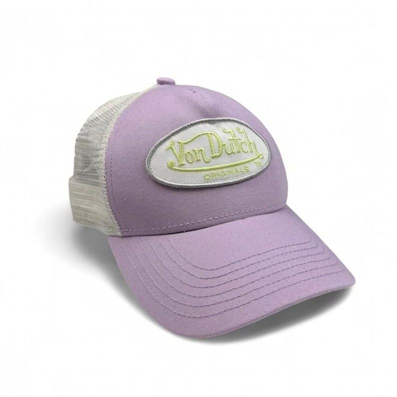 May include: A lavender baseball cap with a curved peak and a mesh back. The front features an oval patch with the text "Von Dutch Originals" in green and white. The cap is a classic trucker style.