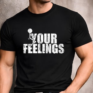 May include: A black short-sleeved t-shirt featuring a white graphic print of a stick figure and the text "YOUR FEELINGS" in a distressed, weathered font style. The design is centered on the chest of the garment, which has a crew neckline.