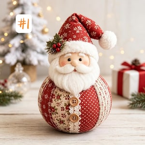 May include: A round fabric Santa Claus figurine featuring a red hat with white snowflake patterns and a white pom-pom. The body is made of red fabric with floral and polka dot panels, accented by two wooden buttons and a white lace trim down the center.