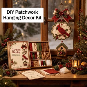 May include: A DIY patchwork hanging decor kit titled Cardinal Blessing, featuring a box with fabric swatches, thread, buttons, and stuffing. A finished hanging ornament displays a red cardinal on a branch above a birdhouse with a red bow.