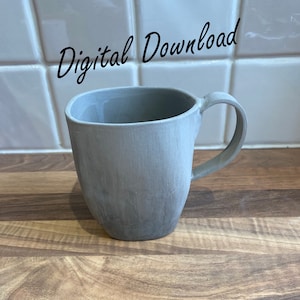 Op de afbeelding: Een grijze keramische mok met een afgeronde handgreep. De mok staat op een houten oppervlak.