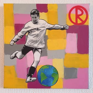 May include: A square canvas painting featuring a grayscale figure kicking a soccer ball designed as a globe. The background consists of a grid of yellow, pink, and gray rectangular blocks. A red circular logo with the letter R is in the top right.