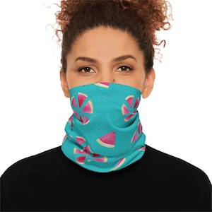 Könnte beinhalten: Eine türkisblaue Gesichtsmaske mit einem sich wiederholenden Muster aus Wassermelonenstücken. Die Wassermelonenstücke sind rosa und rot mit schwarzen Kernen.