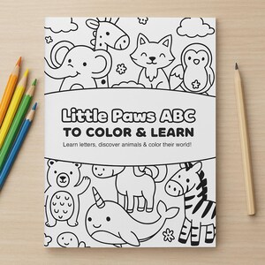 Può includere: Un libro da colorare intitolato "Little Paws ABC to Color & Learn" con illustrazioni di animali in bianco e nero. Sono presenti matite colorate e una matita di grafite.