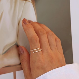 May include: A gold ring with a row of small pearls and a row of small clear stones.