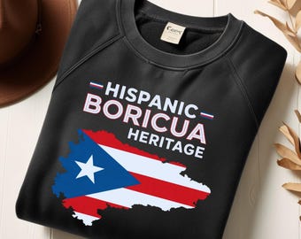 May include: Black crew neck sweatshirt with the text "HISPANIC BORICUA HERITAGE" in white and pink, with a Puerto Rican flag design. The sweatshirt is a casual garment.