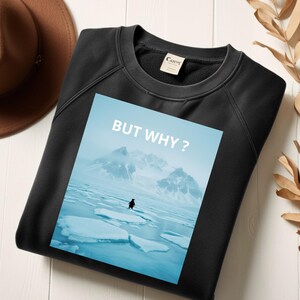 Könnte beinhalten: Schwarzes Sweatshirt mit einer Grafik eines Pinguins auf Eis und dem Text "BUT WHY ?" in Weiß. Das Bild zeigt einen Pinguin auf Eis mit Bergen im Hintergrund. Ein brauner Hut befindet sich in der oberen linken Ecke.