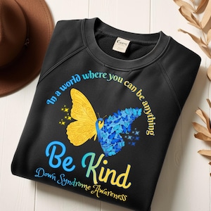 May include: Black sweatshirt with a butterfly design, featuring yellow and blue wings. Text reads "In a world where you can be anything, Be Kind, Down Syndrome Awareness."