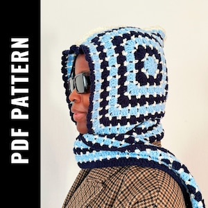 Könnte beinhalten: Ein blauer und weißer Häkel-Kapuzen-Schal mit geometrischem Muster. Der Schal wird von einer Person mit Sonnenbrille getragen.