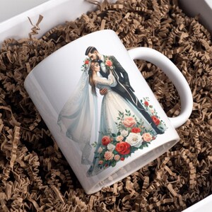 May include: White ceramic mug with a colorful illustration of a bride and groom embracing, surrounded by red, white, and pink flowers.