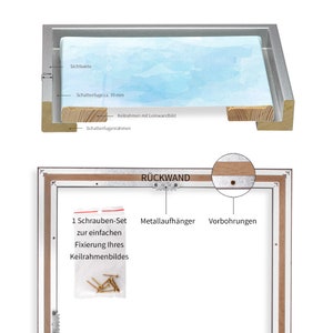 May include: A wooden picture frame with a light blue canvas insert. The frame has a silver metal lip and a shadow gap. The back of the frame shows a metal hanging hook, pre-drilled holes, and a screw set for hanging.