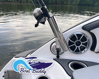 May include: A close-up of a white boat with a fishing rod holder and a speaker. The boat has a black and gray interior and a blue and white logo that says "The Boat Buddy".
