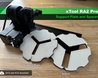 May include: Two laser cutter cut wooden pieces, one labeled "Support Plate" and the other labeled "Spacer". Both pieces are white with a black Y-shaped cutout. The pieces are on a wooden surface.