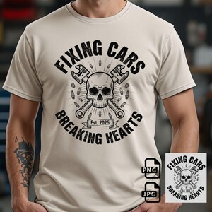 May include: Beige t-shirt with a black graphic. The graphic features a skull with crossed wrenches, surrounded by bullets, and the text "FIXING CARS BREAKING HEARTS Est. 2025". Includes PNG and JPG file icons.