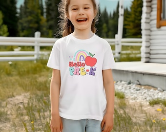 May include: A white t-shirt featuring the words "Hello PRE-K" in a colourful design. The graphic includes a rainbow and a red apple. The t-shirt is worn by a young person.