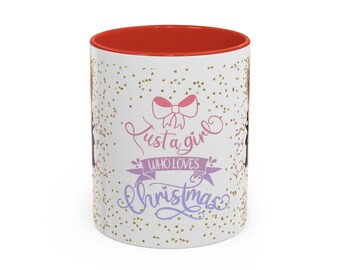 May include: White ceramic mug with a red interior, featuring the text "Just a girl who loves Christmas" in pink and purple script. The mug is decorated with gold glitter and a pink bow.
