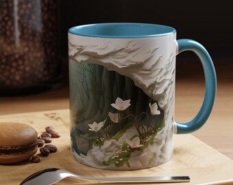 May include: A white ceramic mug with a blue rim and handle. The mug features a colourful illustration of a cave opening with white flowers and green foliage.