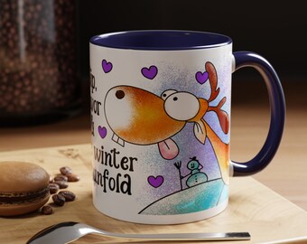 May include: White ceramic mug with a blue interior and handle. The mug features a cartoon reindeer with a long tongue, purple hearts, and the words "sip, savor, winter unfold". A snowman is also depicted.