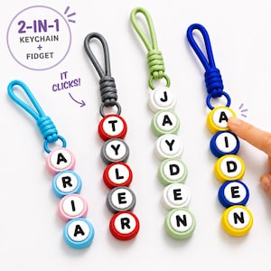 May include: Four 2-in-1 keychain and fidget toys with loops. Each features circular buttons with black letters spelling ARIA, TYLER, JAYDEN, and AIDEN. The buttons are colored pink, blue, red, gray, green, white, and yellow. Text reads 2-IN-1 KEYCHAIN + FIDGET and IT CLICKS!