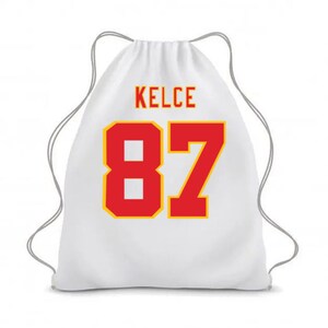 May include: White drawstring bag with the name "KELCE" and the number "87" printed in red with a yellow outline.