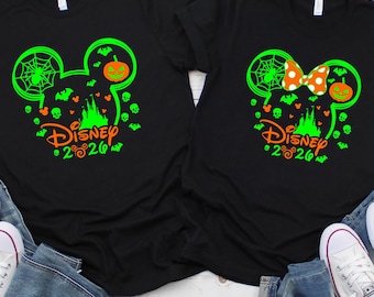 May include: Two black t-shirts with Halloween-themed Disney graphics. One features a Mickey Mouse head with a spiderweb, pumpkin, and castle. The other has a Minnie Mouse bow. Both shirts have "Disney 2020" text.