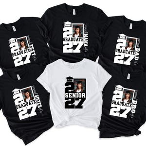 Op de afbeelding: Een collectie van vijf t-shirts met een afstudeerthema. Vier zwarte shirts tonen de tekst 'proud [familielid] of a GRADUATE 27' met een foto. E&eacute;n wit shirt bevat de tekst 'SENIOR 27' en een foto van een afgestudeerde.