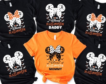 May include: Five short-sleeved t-shirts featuring a Mickey Mouse head silhouette graphic with a castle, bats, and a witch. Four shirts are black, one is orange. Text includes 2026, Disney Halloween, and the labels Daddy and Mommy.
