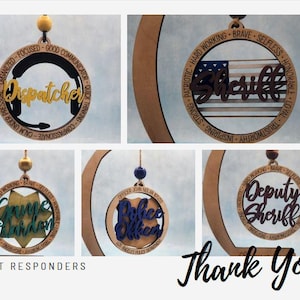 May include: Set of five wooden ornaments with different designs for first responders. Each ornament features a different job title, including "Dispatcher", "Sheriff", "Police Officer", "Deputy Sheriff", and "Grounds Warden".
