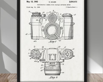 May include: Framed print featuring a vintage camera patent illustration. The diagram shows the camera's front and top views, with detailed labels and the date May 15, 1962. The text includes "PHOTOGRAPHIC CAMERA WITH COUPLED EXPOSURE METER."