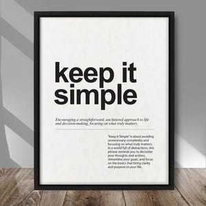 Peut inclure: Impression encadrée en noir avec l'inscription "keep it simple" en gras, en noir. L'impression comprend une définition et une explication de la phrase. L'impression est affichée sur une surface en bois.
