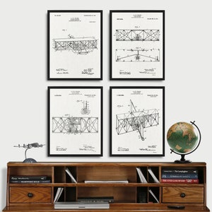 Peut inclure: Ensemble de quatre tirages encadrés noirs de dessins de brevets d'avions vintage. Les dessins sont en noir et blanc et montrent différentes vues de l'avion. Les tirages sont sur fond blanc et sont exposés sur une étagère en bois avec des livres et un globe terrestre.
