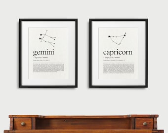 May include: Two black framed prints with white backgrounds, each featuring a constellation and its corresponding zodiac sign. The left print shows the Gemini constellation with the word "gemini" and its definition below. The right print shows the Capricorn constellation with the word "capricorn" and its definition below.