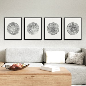 May include: Set of four black and white framed prints featuring abstract tree ring patterns. The prints are displayed on a white wall above a grey sofa.