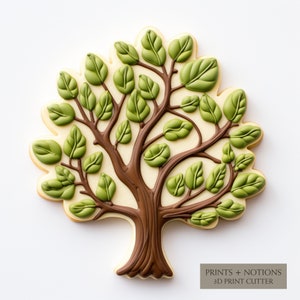 May include: A brown and green cookie shaped like a tree with a detailed design. The cookie is decorated with green icing leaves and a brown icing trunk. The text "PRINTS + NOTIONS 3D PRINT CUTTER" is printed on the bottom right corner of the image.
