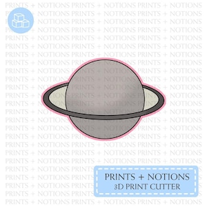 May include: A gray and white planet with a black ring around it. The planet is outlined in pink. The text "PRINTS + NOTIONS 3D PRINT CUTTER" is in a blue box.