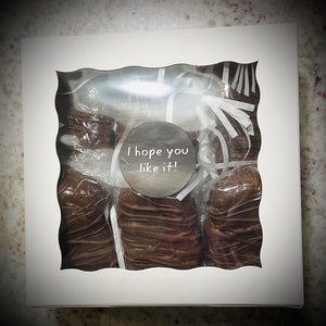 May include: A white gift box with a clear window showing several chocolate-covered treats inside. The box has a white circle sticker with the text "I hope you like it!" on it.