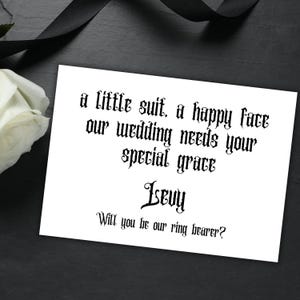 Peut inclure: Une carte blanche avec du texte noir qui dit "a little suit, a happy face our wedding needs your special grace ISBUY Will you be our ring bearer?"